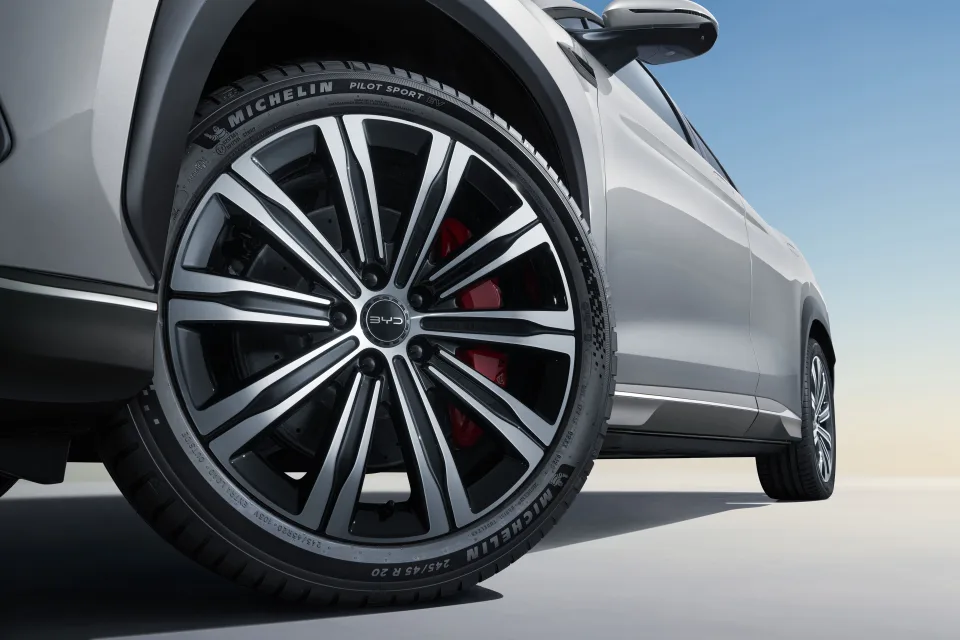 Close-up van een BYD-lichtmetalen velg met een Michelin Pilot Sport-band en rode remklauw, gezien vanuit een lage hoek.