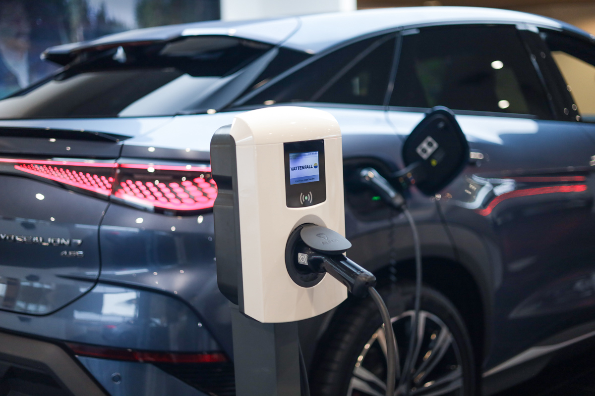Elektrische auto wordt opgeladen bij een Vattenfall-laadpaal, met de stekker aangesloten op de achterzijde van het voertuig. De auto heeft een moderne, gestroomlijnde vorm en opvallende achterlichten.